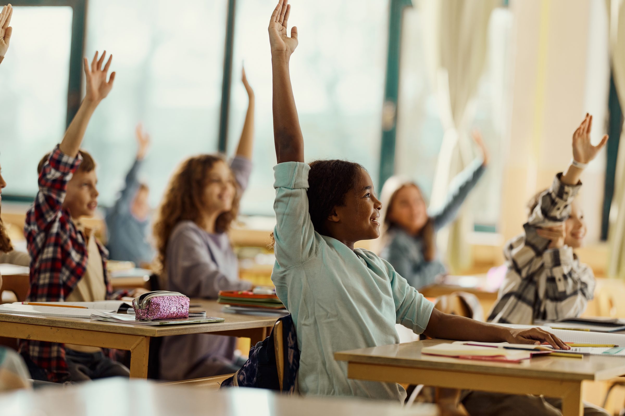 Elementary school students raising their hands in a California classroom